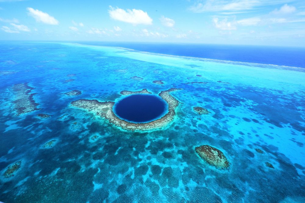 Aerial view of Belize’s Great Blue Hole surrounded by turquoise reef