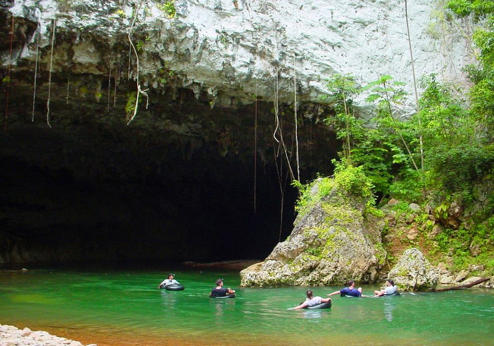 Travelers floating through a broad jungle cave in Belize