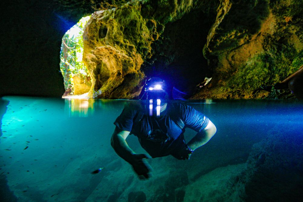 Guide and travelers wading through Actun Tunichil Muknal cave