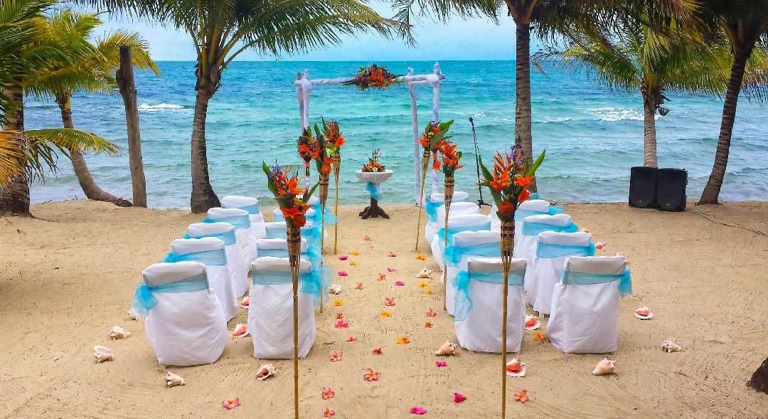 Beach wedding ceremony with a bamboo arch and decorated chairs on the sand
