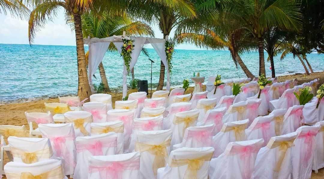 Rows of dressed chairs set for a beach wedding ceremony facing the Caribbean Sea