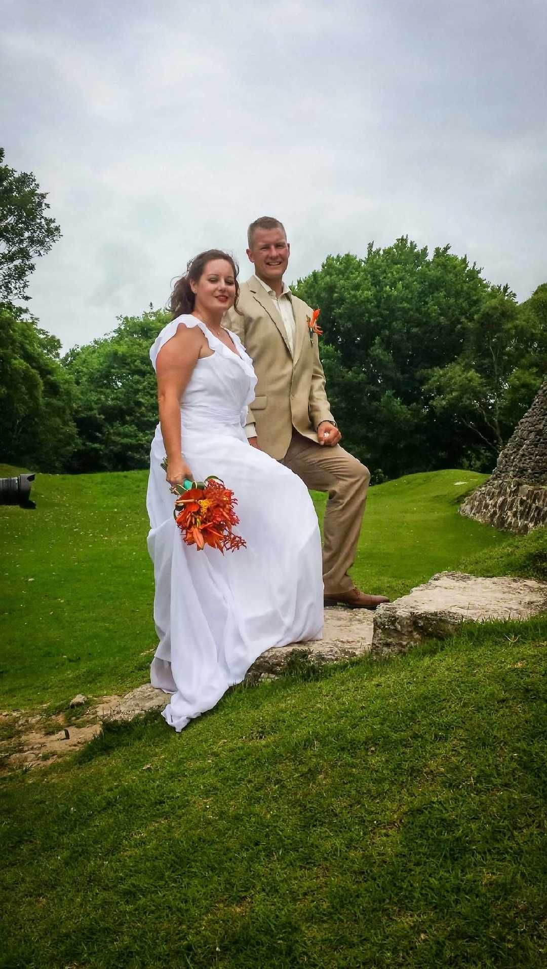 Bride and groom in front of a Maya pyramid, bouquet in hand